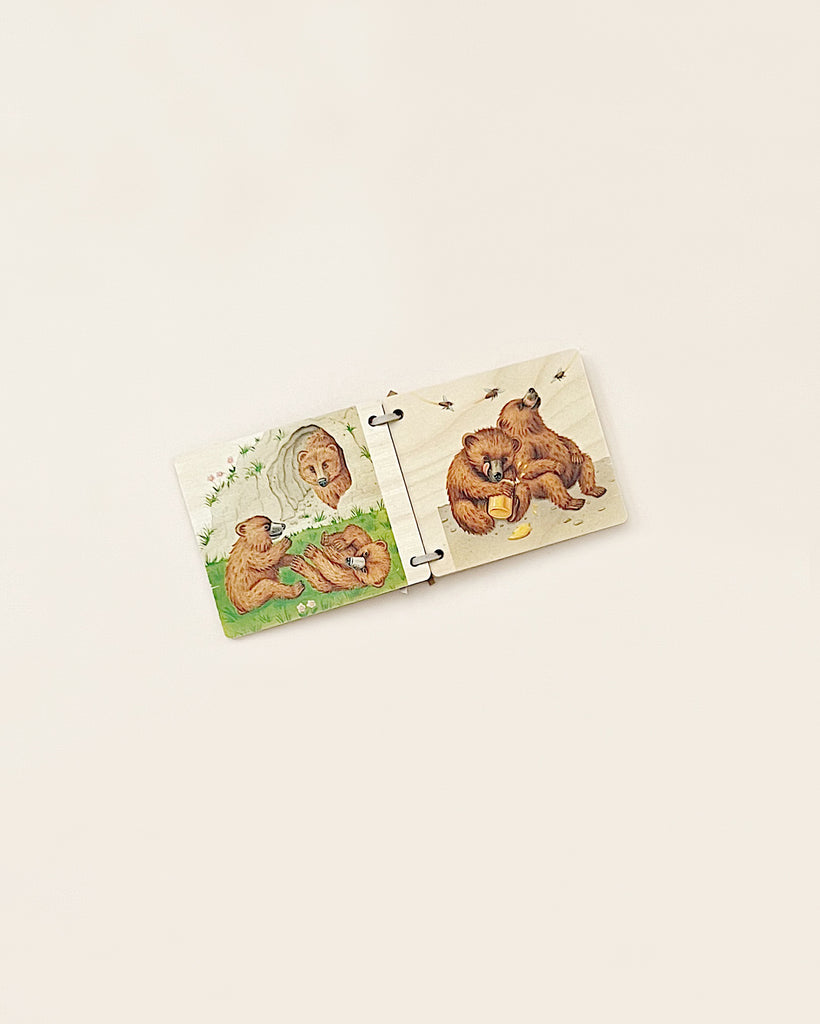 A Wooden Picture Book - Bear with four pieces on a beige background, depicting playful bear scenes: two bears fishing in a stream and two bears picking mushrooms in the forest.