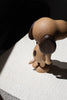 A Boyhood Snoopy, Small figurine, viewed from behind, casting a sharp shadow on a light-textured surface, illuminated by natural light.