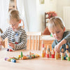 Two young children, focused and engaged, playing with colorful wooden Grapat Buds/Brots on a table in a brightly lit room.