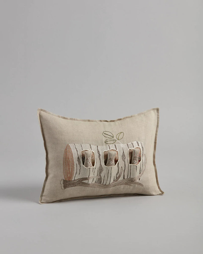The Coral & Tusk Aspen Log Bunnies Pocket Pillow features a beige rectangular shape with an embroidered design of logs, each hosting a bird in a hollow. Minimal leaf details enhance this decorative home decor piece beautifully.