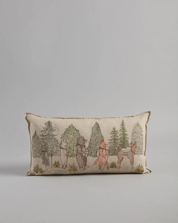 The Coral & Tusk Hikers Pillow showcases woodland friends, including bears and foxes, wandering through an evergreen forest on a neutral background with delicate plants below. (Ships in approximately one week.).