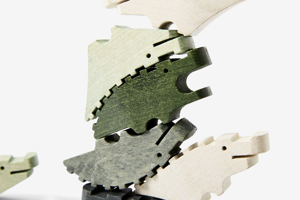 10 wooden stackable crocodile shaped pieces in various shades of green, photographed up close.