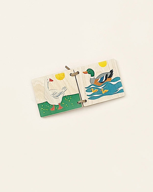 A children's Wooden Picture Book - Animals, made from sustainably harvested trees, depicting colorful painted illustrations of a chicken and a duck, separated by interlocking puzzle pieces on a plain background.