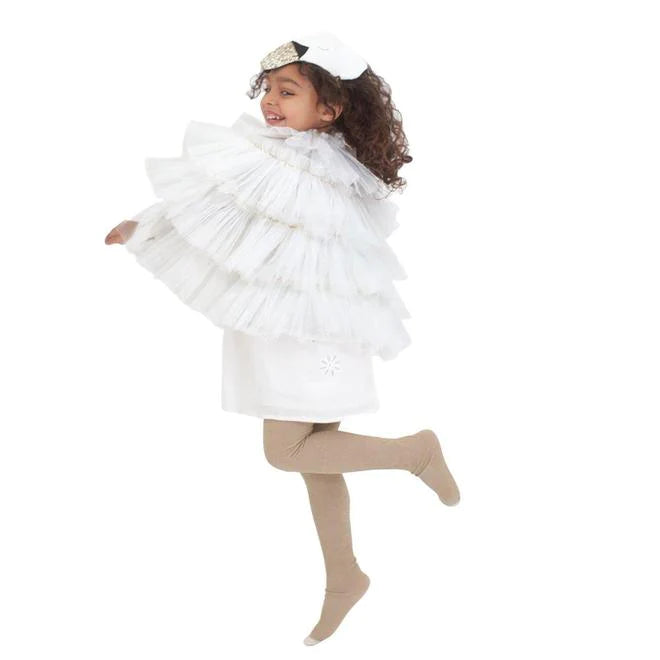 A young girl twirling in a playful pose, wearing the Meri Meri Swan Costume - Final Sale with tulle wings, light brown leggings, and ballet flats.
