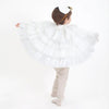 A young child in a Meri Meri Swan Costume spins playfully, presenting the skirt fanned out, against a plain white background. The child's back is to the camera with a focus on the skirt.