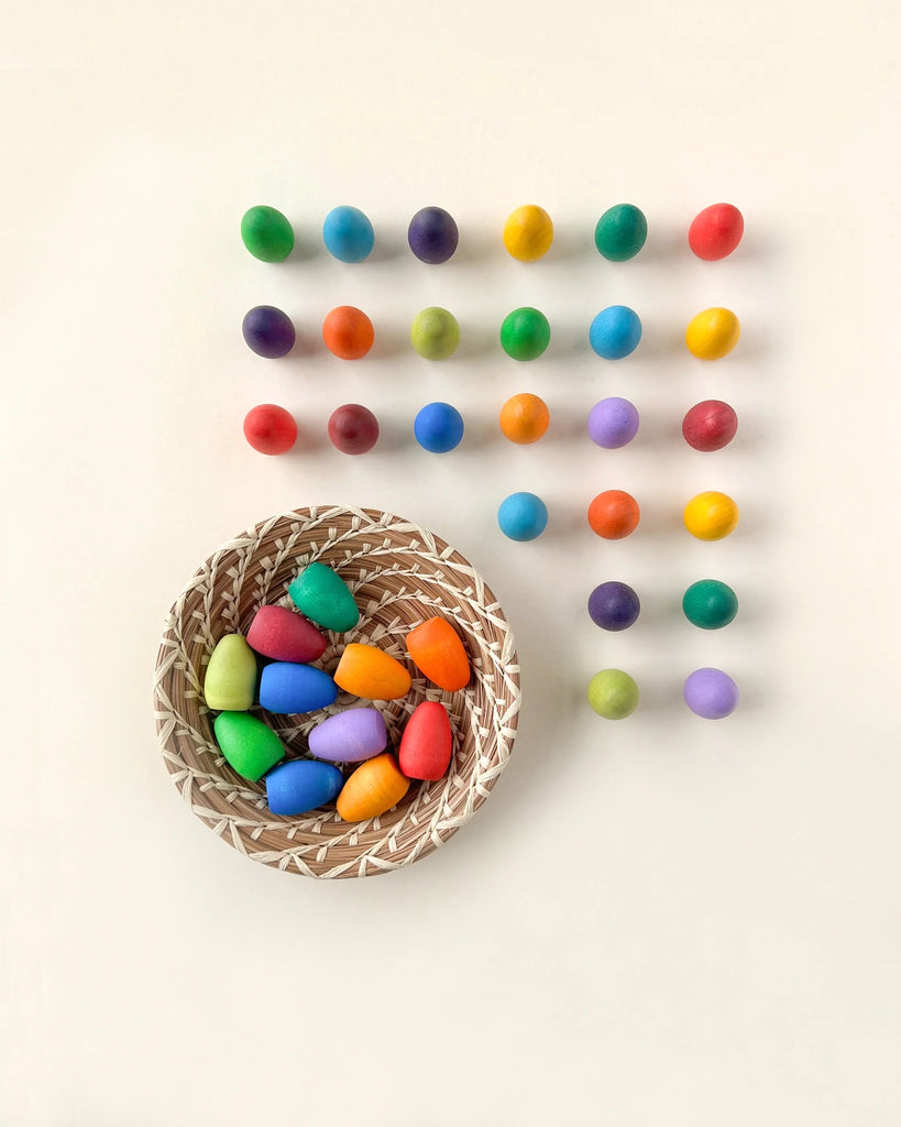 A basket of Grapat Mandala Rainbow Eggs, positioned next to neat rows of multicolored balls arranged in a grid on a light background.
