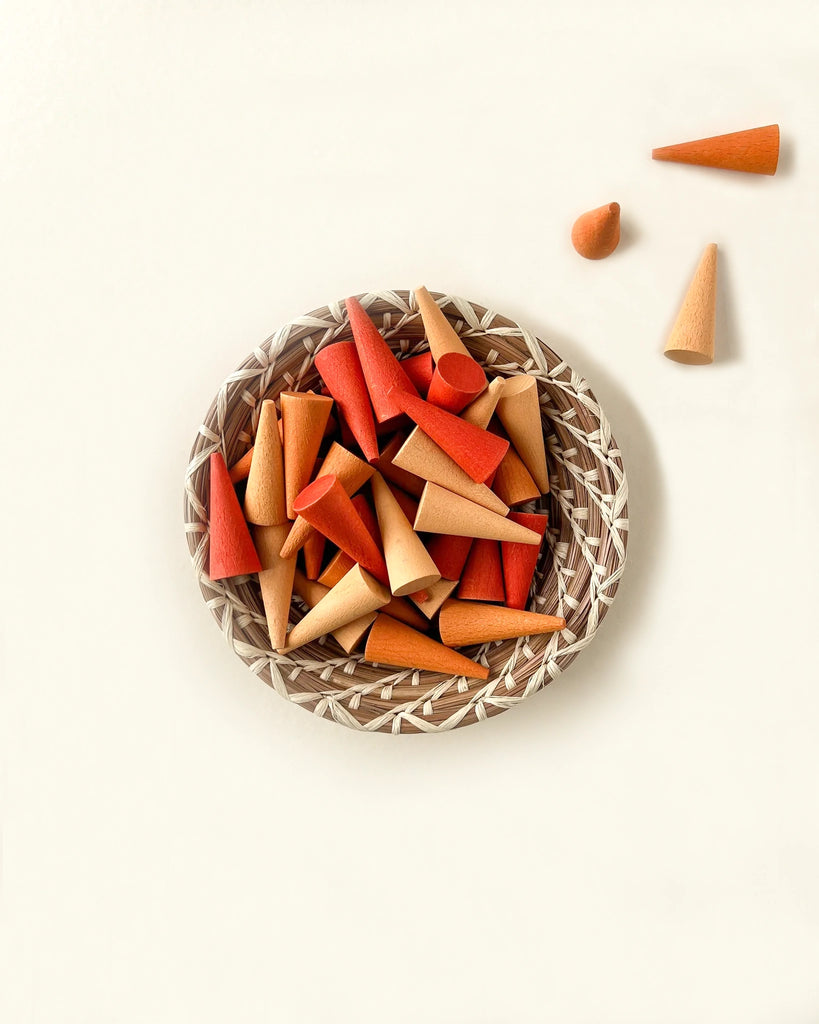 A basket filled with colorful, assorted Grapat Mandala Orange Cones placed on a neutral background, with a few cones scattered outside the basket.