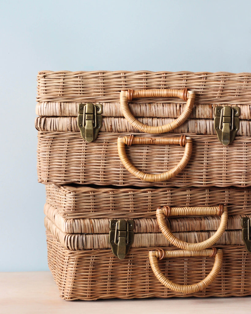 Two stacked Rattan Toaty Trunks with sturdy handles and brass clasps, set against a soft blue background.
