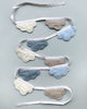 Four strings of Cloud Garland with attached cloth clouds in white, gray, and shades of blue, made from Oeko-tex certified organic cotton, arranged artistically against a pale background.