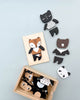 Mix & Match Animal Tiles shaped like animals, including a cat and a fox, are displayed next to and inside a wooden box on a light blue background.