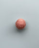 a soft pink felt ball on a light blue background.