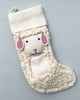 A white, fluffy Handmade Sheep Christmas stocking designed to look like a sheep, featuring textured fleece, pink inner ears, and a cute face, against a light gray background.