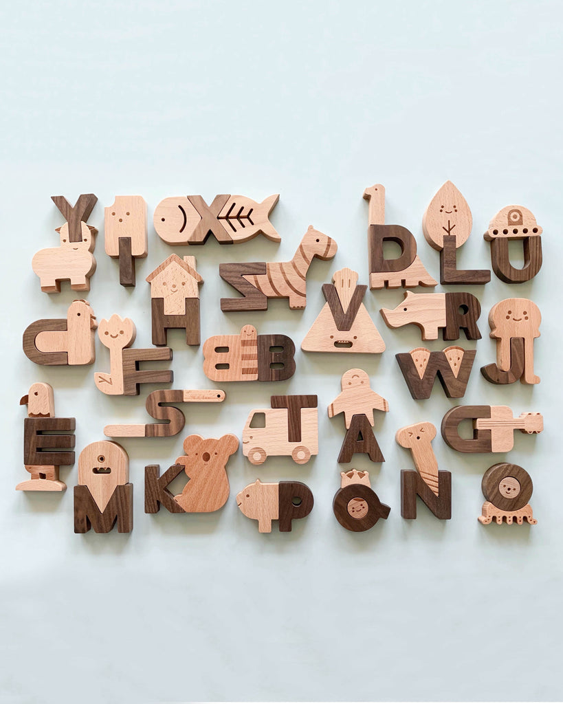 A collection of Ultimate Wooden Alphabet Puzzle blocks with each character shaped into an animal or an object that corresponds with the letter, arranged randomly on a light blue background.