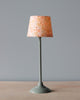 A tall Maileg Miniature Floor Lamp with a grey base and stem, topped with a conical lampshade decorated with orange floral and starburst patterns on a pale background.