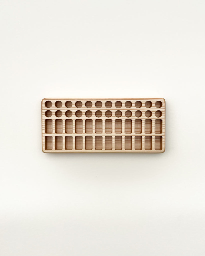 A Crayon Tray For Stockmar - 24 x 24 Slots with multiple rows of circular indentations for educational purposes, placed on a light beige background.