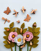 A creative display of Handmade 11-Piece Wooden Insects and flowers, including dragonflies, butterflies, ladybugs, and bees from the wooden insect set, artistically arranged on a light gray background.