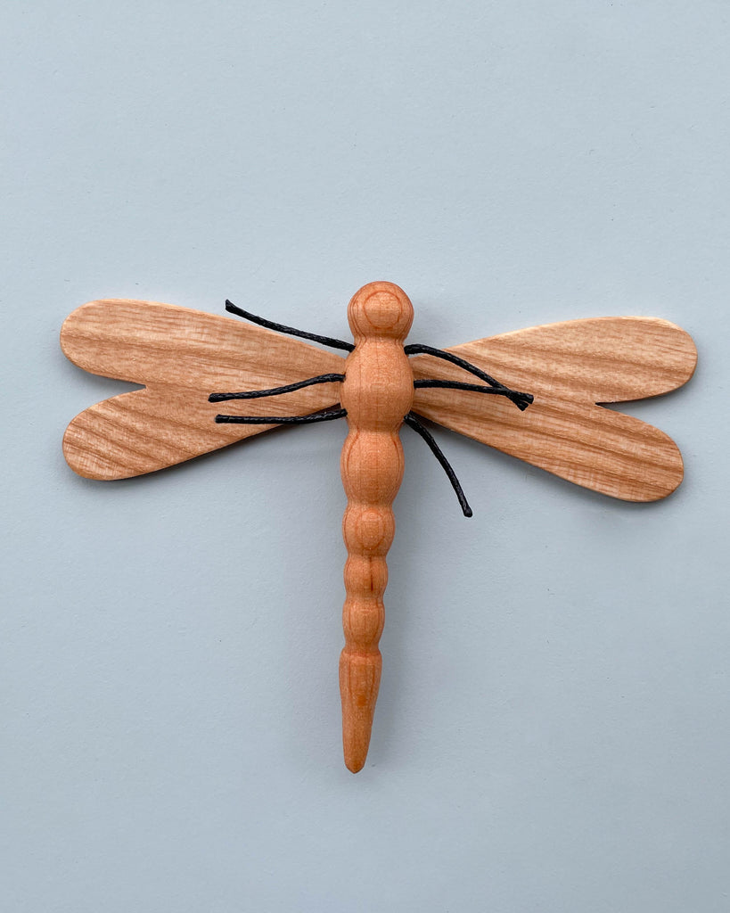 A Handmade 11-Piece Wooden Insects figurine, hand-crafted from alder ash wood, with delicately carved wings and body, displayed against a plain light blue background.