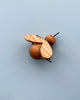 A hand-crafted Handmade 11-Piece Wooden Insects airplane made of two round, brown beads as the body and a light wooden piece as the wings, set against a plain light blue background.