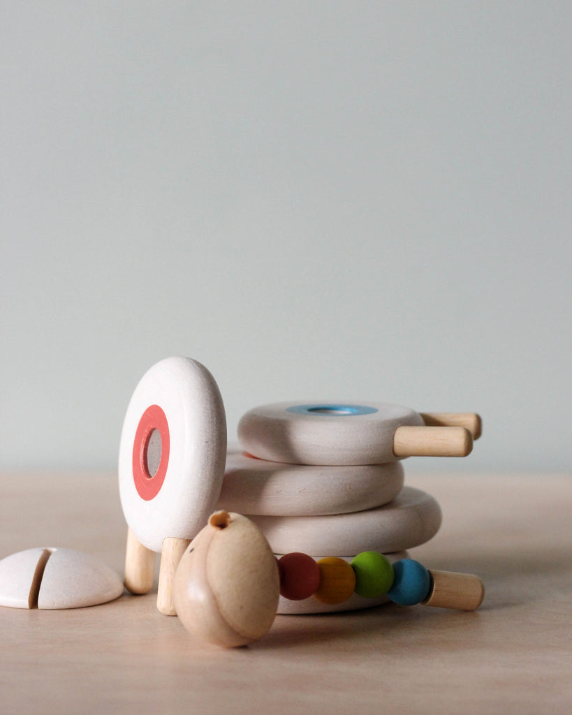 A wooden educational toy Lacing Wooden Sheep with colorful beads on its wheels and a stackable shell made of circular rings, set against a soft neutral background.