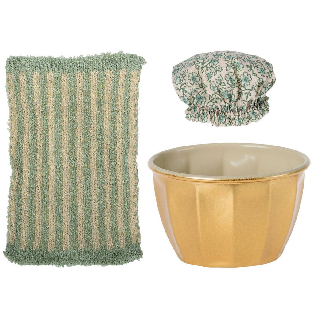 A green striped kitchen sponge, a gold-colored ceramic bowl, and a printed scrubbing pad featuring Maileg Wellness Mouse, Big Sister (Mint) on a white background.
