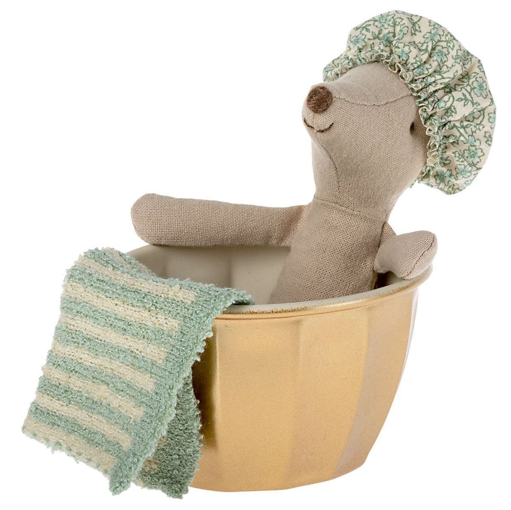A Maileg Wellness Mouse, Big Sister (Mint) wearing a shower cap sits inside a small yellow bowl, partially covered with a green and blue striped knit blanket.