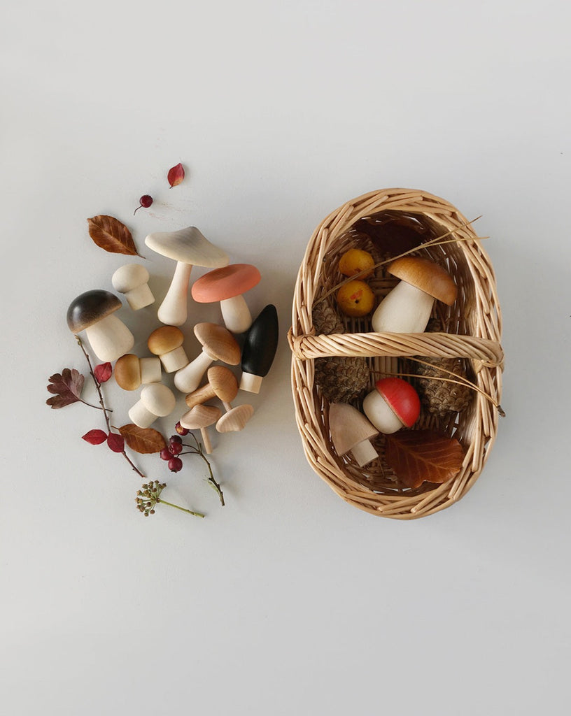 Wooden mushroom toys in a woven basket, laying flat on a surface.