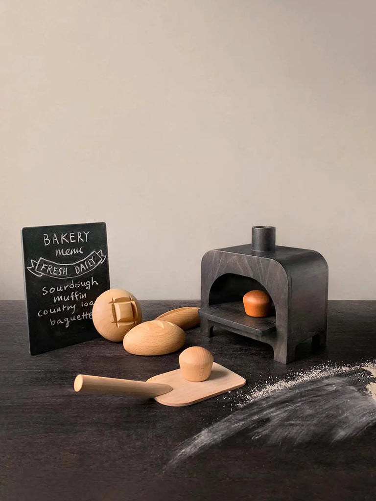 Miniature artisan My Bakery scene with a small cast iron oven, a rolling pin, dough, a wooden spoon, and a bakery menu board listing various bread types including sourdough bread, all set against