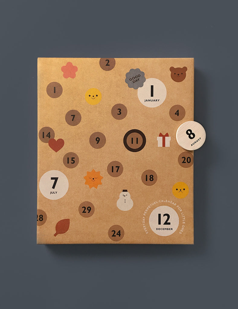 A My Calendar with various sized magnetic discs, each featuring numbers, icons like leaves and snowmen, and months like "january" and "july" on a textured brown background.