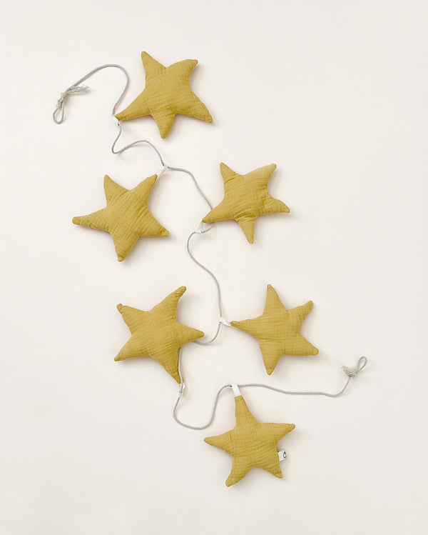 A string of six yellow star-shaped cushions linked by a white cord on a pale background, arranged in a slightly curved line to form a Handmade Star Garland.