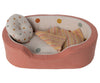 A toy dog bed with a pillow and a blanket.