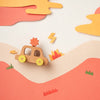 A creative paper art scene featuring My Little Car toy car traveling through a layered landscape of soft pink and orange hills, with paper cut-outs of clouds, lightning bolts, and small green shrubs.