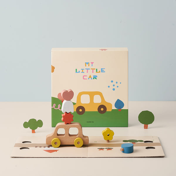 A children's book titled "My Little Car" displayed with an emotional My Little Car toy and colorful cutout trees and shapes on a track, set against a plain light blue background.