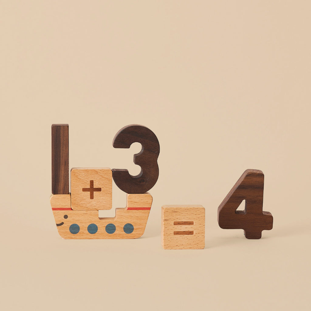 Numbers Play Block Set wooden blocks arranged to depict a math equation, "3 + 1 = 4," with the blocks stylized as a small ship and numbers on a beige background.
