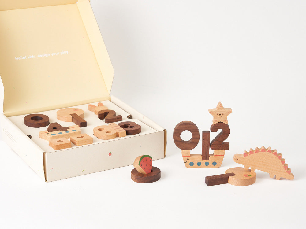 An Numbers Play Block Set displayed beside an open box, featuring blocks shaped like numbers and animals, including a star, dinosaur, and watermelon, on a white background.