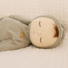Soft doll with white skin tone in sage colored pajamas sleeping. 