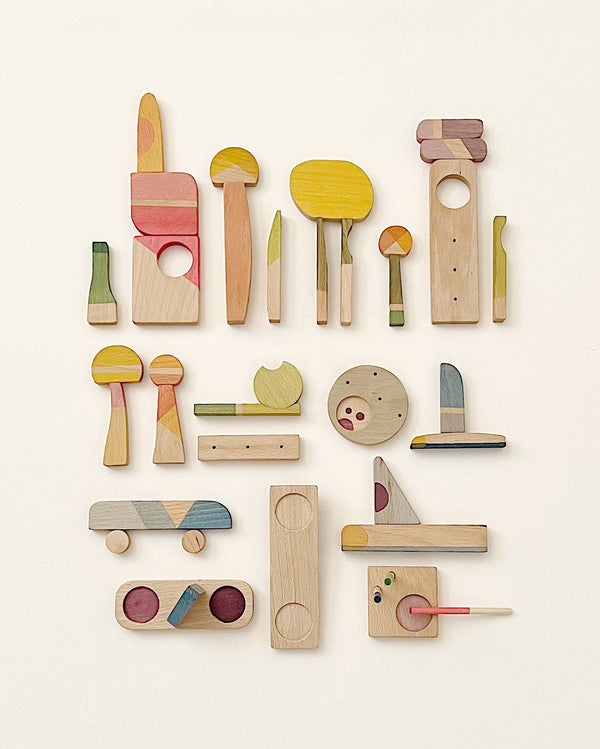 An assortment of colorful, abstract wooden shapes laid out on a light background, reminiscent of playful, artistic interpretations of tools and objects, all crafted from sustainable wood like the Grapat Happy Place.