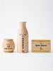 Three wooden containers from the Milton & Goose Pantry Play Food Set are arranged against a white background. From left to right, there is a round jar labeled "Manuka Honey," a tall bottle labeled "Apple Cider Vinegar," and a rectangular box labeled "Flaky Sea Salt." Each item features minimalist and uniform labeling.