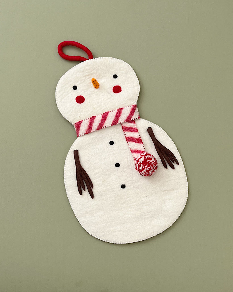 A Handmade Snowman Christmas Stocking with a striped scarf and a pom-pom hat, featuring button eyes and a carrot nose, on a green background.