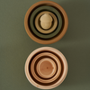 Top view of two sets of Raduga Grez Nesting Acorns in different shades placed on a green background. The upper set includes a small sphere, creating a centered gradient effect.