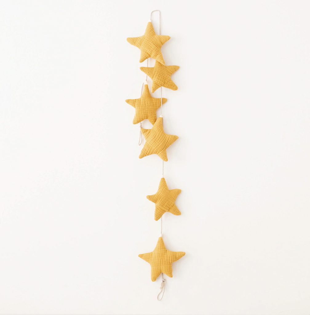 A vertical garland of Handmade Star Garland pillows handmade from organic cotton, each star connected by a simple string, hanging against a plain white background.