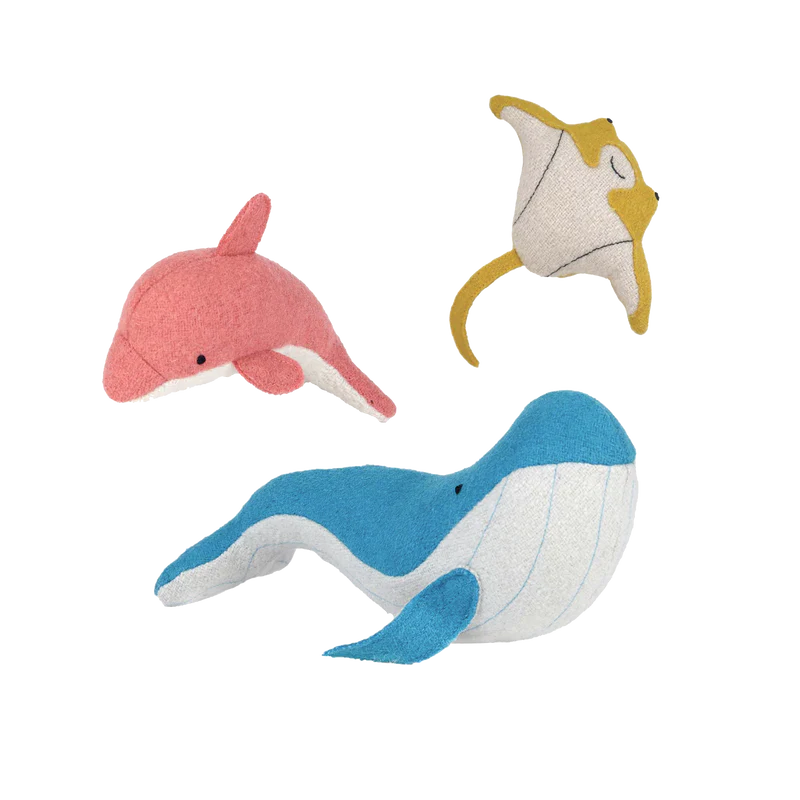 Three colorful handmade Olli Ella Holdie Folk Felt Ocean Animals including a pink dolphin, a yellow and white cat, and a blue and white whale, displayed on a black background.
