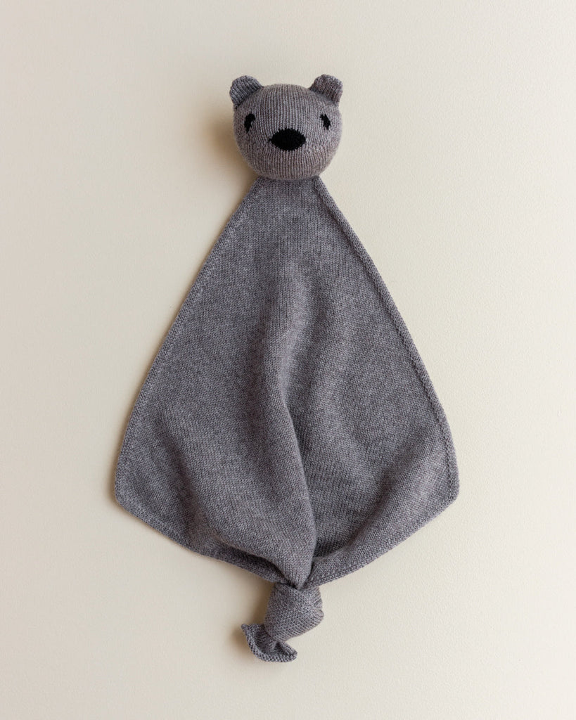 A small merino wool lovey in grey color with a head of a teddy bear at the top.