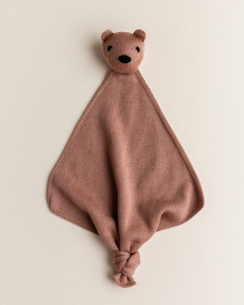 A small merino wool lovey in terracotta color with a head of a teddy bear at the top.