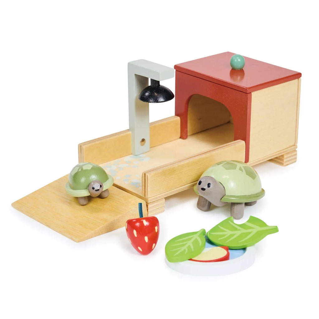A Tender Leaf dolls house featuring a cozy home with a red roof, the Tortoise Pet Set, a lamp, and a set of wooden fruits on a white background.