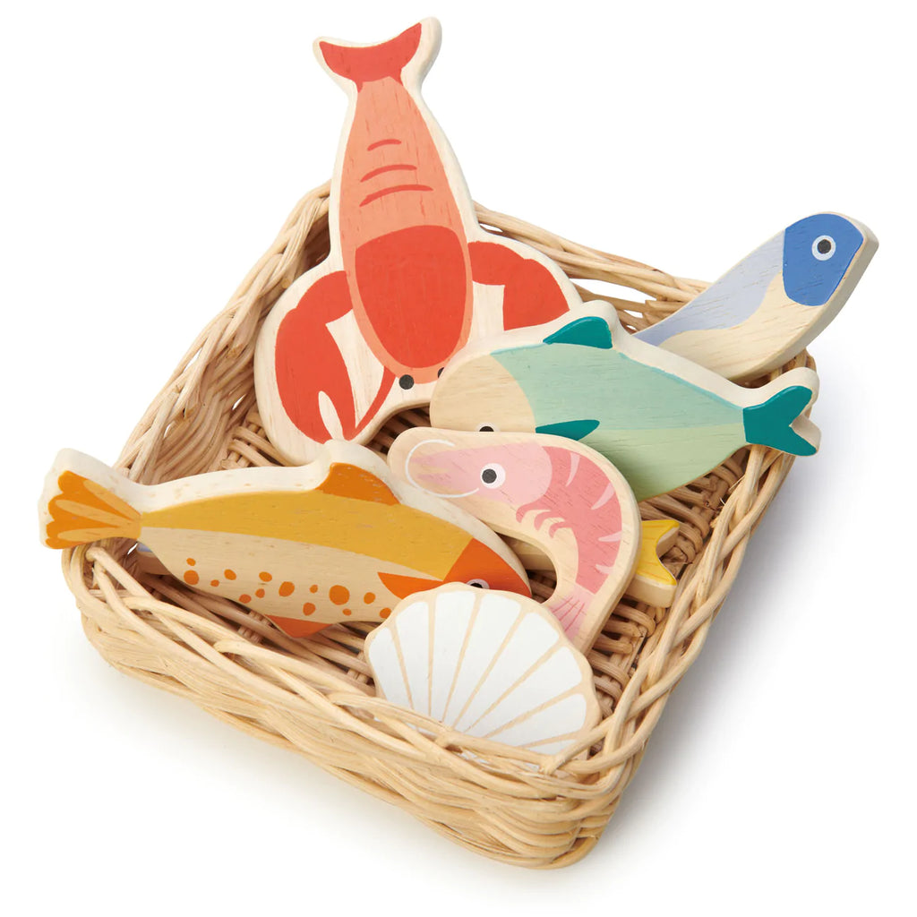 A collection of colorful wooden fish and a seashell toy pieces neatly arranged inside a small handcrafted Market Basket on a white background.