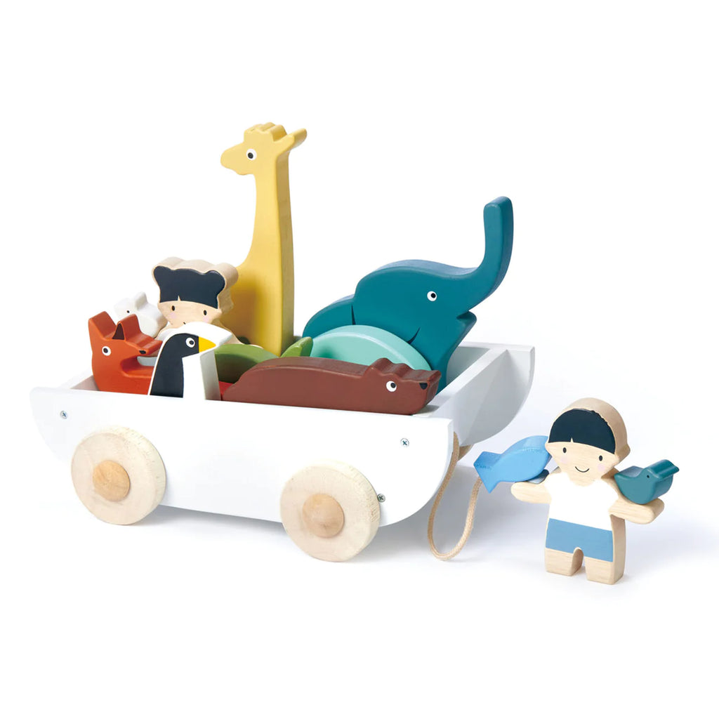 A child's wooden toy set made from sustainable rubber wood featuring The Friend Ship Pull Toy, which includes a white cart filled with colorful animal figures including a giraffe, elephant, and others, and a toy figure of a boy with blue wings.
