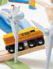 A colorful toy train labeled "Mountain View Train set" runs on wooden tracks past model wind turbines. The scene includes blue and yellow toy elements in the background.