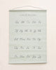 A Gathre Cursive Poster hanging on a wall, featuring uppercase and lowercase letters a to z in black script on a pale green background with the title "cursive alphabet" at the top.