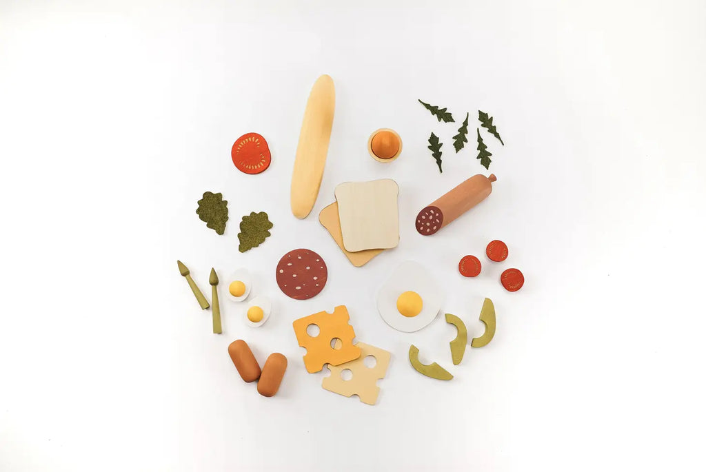 Assorted Sabo Concept handmade wooden play food items including fruits, vegetables, bread, cheese, and meat, neatly arranged on a white background and coated in non-toxic water-based paint.