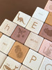 Alphabet Wooden Blocks - Rose crafted from linden wood, featuring letters and illustrations corresponding to different objects or animals like dinosaur, bear, butterfly, and jellyfish, arranged on a table.